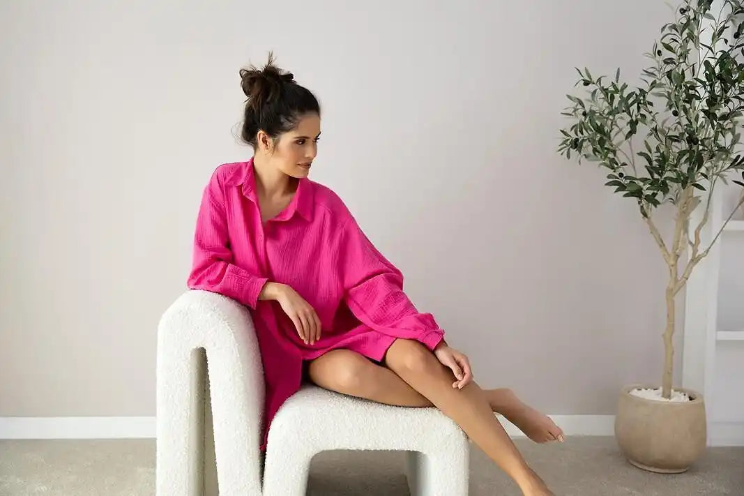 Una donna con una camicia lunga a maniche lunghe, oversize color fucsia.